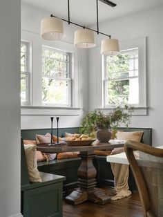 a dining room table with two chairs and a bench in front of it, next to windows