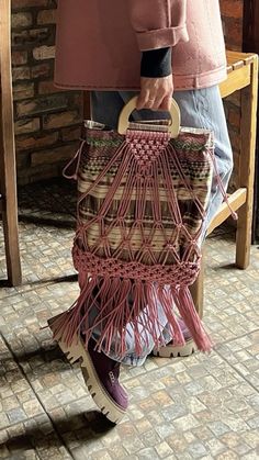 a woman holding a pink purse on top of a wooden chair