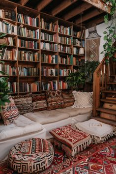 a living room filled with lots of furniture and bookshelves full of books next to a stair case