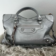 Large Size Balenciaga Bag In Rare Silver. There Is Wear On The Handles And Corners Of The Bag. Please Refer To Pictures. Has A Lot Of Life Left And Is A Unique Find. See Photos With Tape Measure For Dimensions. Designer Silver Satchel With Detachable Strap, Designer Silver Crossbody Satchel, Designer Silver Satchel With Double Handle, Designer Silver Tote Satchel, Designer Silver Satchel Tote, Vintage Balenciaga Bag, Balenciaga Glitter Bag, Balenciaga Hourglass Bag Silver, Silver Shoulder Bag With Silver-tone Hardware For Shopping