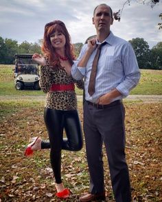 a man standing next to a woman in black leggings and a tie on