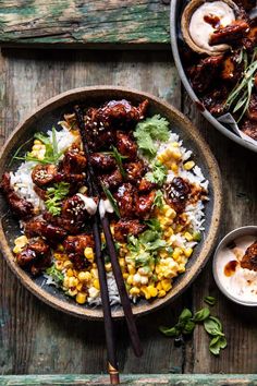 a bowl filled with meat and rice on top of a wooden table