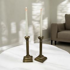 two candles sitting on top of a white table