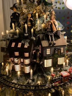 a christmas tree decorated with dolls and lite up houses on top of each other