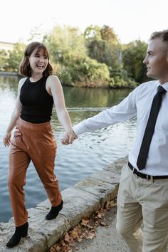 a man and woman are holding hands by the water