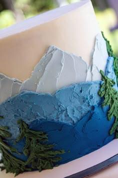 a close up of a cake with frosting and trees on the top, along with other decorations