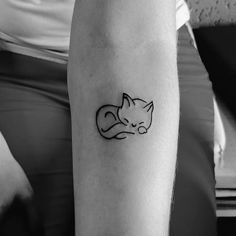 a black and white photo of a cat tattoo on the left arm, with a line drawing of a sleeping cat