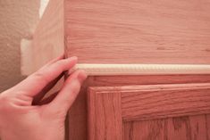 a person is holding the door handle on a wood paneled door with white trim