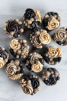 cupcakes with chocolate frosting and gold decorations on a marble countertop, top view from above