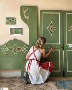 a woman in a white dress painting a green door