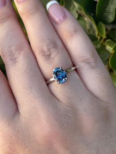 a woman's hand with a ring on it and a blue stone in the middle