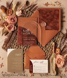 the wedding stationery is laid out on top of each other with flowers and feathers