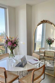 a table with chairs and a laptop on it in front of a large window overlooking the city