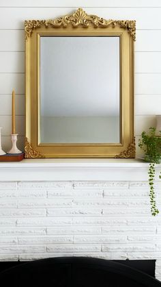 a white brick fireplace with a gold framed mirror above it