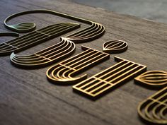 a wooden table topped with gold and black metal logo art pieces on top of it