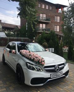 a white car with flowers on the hood parked in front of a brick apartment building