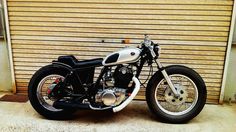 a black and white motorcycle parked in front of a garage door next to a building