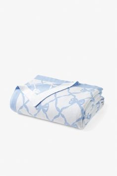 the blue and white blanket is folded on top of each other, with an intricate pattern