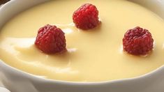 three raspberries are placed on top of the cream in this bowl, ready to be eaten