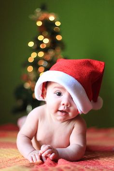 a baby wearing a santa hat on top of a bed