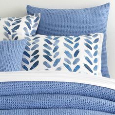 a bed with blue and white pillows on top of it