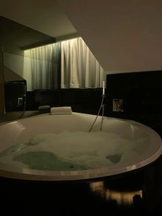 a large bath tub sitting in a bathroom next to a sink and toilet paper dispenser