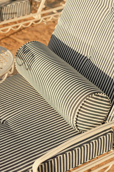 Close-up of a striped chaise lounge with a cylindrical bolster pillow, ideal for sophisticated outdoor relaxation. Relaxation Space, Bolster Pillow, Navy Stripes, Lounge, Sofa, Pillows, Design, Chaise Longue