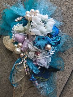 a blue and white brooch with pearls on it's side sitting on the ground