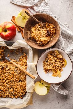 an apple crisp on top of a table next to two bowls with apples and spoons