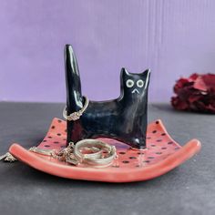 a black cat figurine sitting on top of a plate