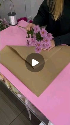 a woman is making some flowers out of brown paper and pink tissue on a table