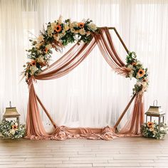 an arch decorated with flowers and greenery for a wedding or reception ceremony is set up in front of a white drapes