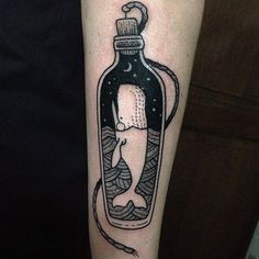 a black and white photo of a bottle with a cat in it on the arm