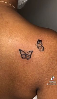 the back of a woman's shoulder with two butterflies on it