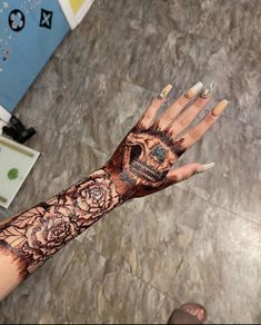 a woman's hand with a skull and roses tattoo on it