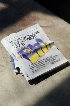 a newspaper sitting on top of a cement floor next to a blue and yellow object