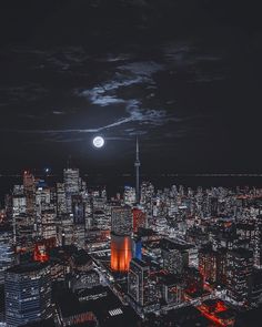 the city is lit up at night and it's full moon