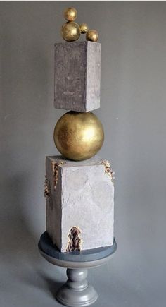 three gold balls are stacked on top of each other in front of a gray background