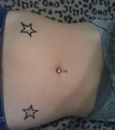 a woman's stomach with three stars on it and a piercing in the middle