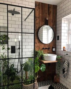 a bathroom with black and white tiles, a round mirror, potted plants and a sink