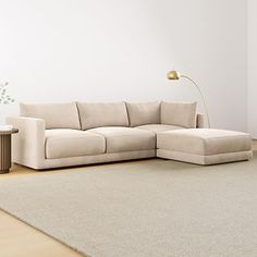 a white couch sitting on top of a wooden floor next to a table and lamp