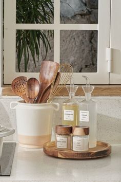 kitchen utensils and wooden spoons sit on a counter