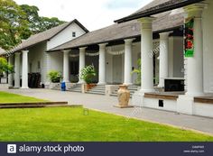 an old white house with columns and pillars in the front yard, on a cloudy day