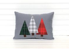 a gray pillow with three christmas trees on the front and one is red, white and green