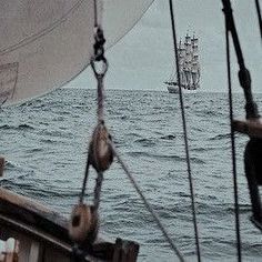 an old ship sailing in the ocean on a cloudy day with another boat behind it