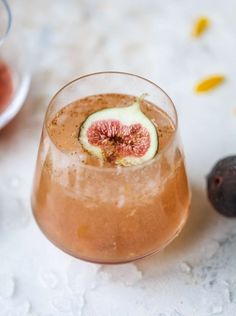 a close up of a wine glass filled with liquid and sliced figs on the side