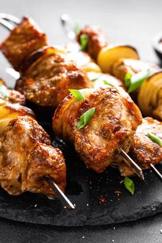 skewered meat and potatoes on a black plate