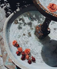 an outdoor fountain with roses on the bottom and water running down it's sides