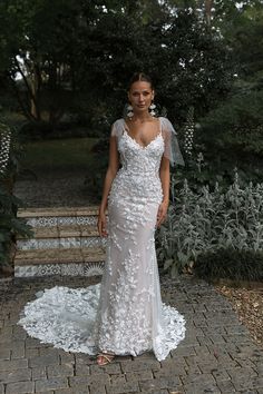 a woman in a wedding dress standing on a brick walkway