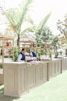 two men are sitting at the bar in front of some wine bottles and glasses on it